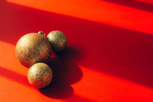 Três Bolas Natal Douradas Fundo Vermelho Brilhante Com Sombras Contrastantes — Fotografia de Stock