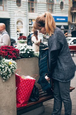 Şehirden alışveriş. Gözlüklü, rahat gri-mavi yelekli, ciddi, genç ve güzel bir kadın şehirde vakit geçiriyor. Yaşam biçimi