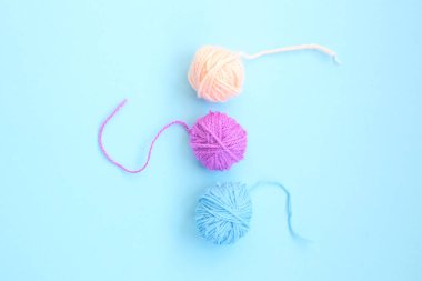 Açık mavi arkaplanda fotokopi alanı olan üç renkli yün iplik. Kapat.