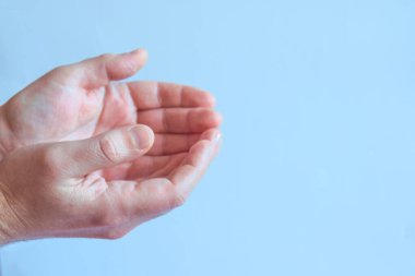 Güzel, boş adamların elleri mavi arka planda avuç içlerini tutuyor. Yan görünüm