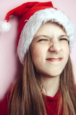 Gülümseyen, uzun saçlı, pembe arka planda tüylü Noel Baba şapkası takan güzel bir kız..