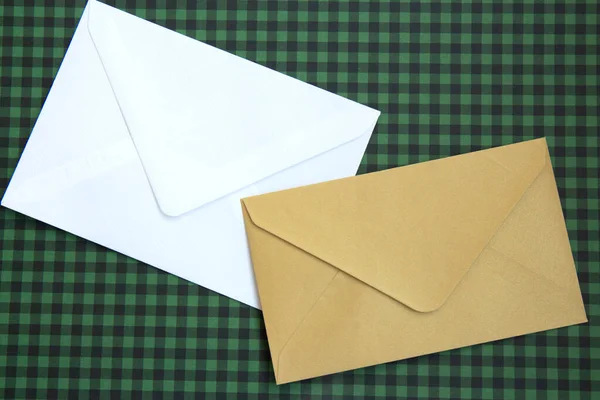 White and beige envelopes and on a green checkered background. Blank template