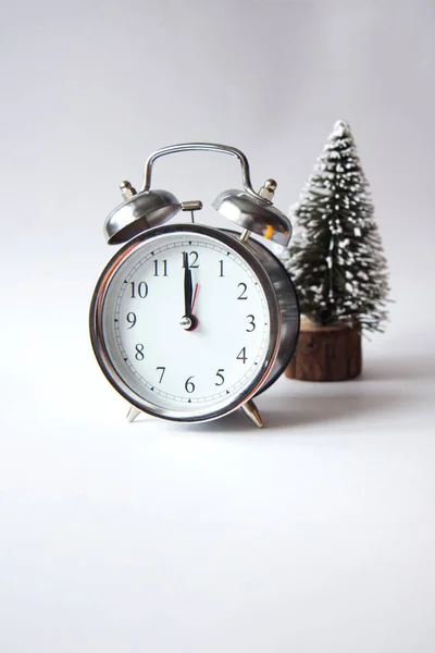 Beautiful vintage silver alarm clock with christmas tree on a gray background. Time concept. Holiday routine. Side view, copy space. Colors 2021