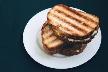 Koyu arkaplanda beyaz tabakta yumurtalı tost sandviçi. Kahvaltıda kızarmış ekmek. Yan görünüm