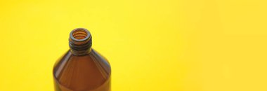 Açık sarı arka planda boş kahverengi ilaç şişesi kozmetik sıvısı. Organik, sıfır atık kozmetik kavramı. Pankart