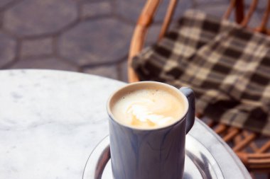 Bir fincan cappuccino, bir kafede, demir bir tepside.