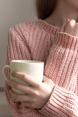 Sarı saçlı, pembe kazaklı, beyaz fincanlı güzel bir kız.