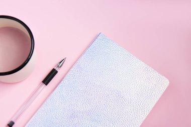Beyaz beyaz sayfalı beyaz bir defter, pembe arka planda kakaolu bir kalem ve demir turuncu bardak. Düz yatıyordu
