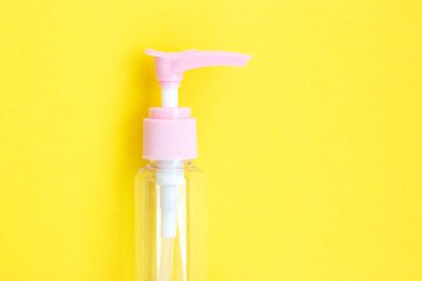 Krem, şampuan ve gölgeli parlak sarı kağıda serum koymak için kozmetik kavanozu hazırla. Boş plastik portatif krema kavanozu ve sıvı kabın üst görüntüsü. Kapat.