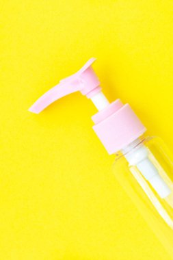 Krem, şampuan ve gölgeli parlak sarı kağıda serum koymak için kozmetik kavanozu hazırla. Boş plastik portatif krema kavanozu ve sıvı kabın üst görüntüsü. Kapat.