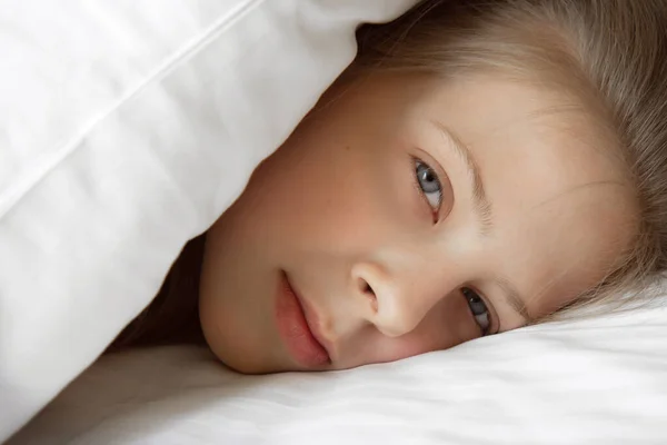 Girl peeking out from under the covers in bed