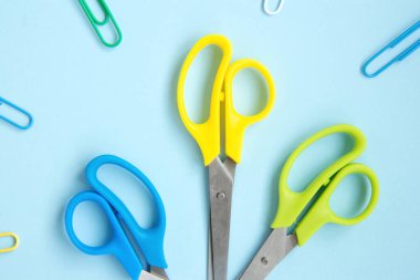 Mavi arka planda mavi, sarı ve yeşil makas seti. Okul kırtasiyesi ve malzemeleri. Okula geri dönmek, evde yaratıcı çalışma alanı. Rengarenk kırtasiye seti. Düz yatıyordu