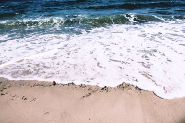 Derin mavi okyanus dalgaları kumlu sahile yuvarlanıyor. Denizin Ufku