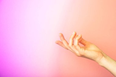 Çok renkli neon arka planda izole edilmiş güzel bir kadın eli. Avuç içi yukarı, yakın. Yüksek çözünürlüklü ürün