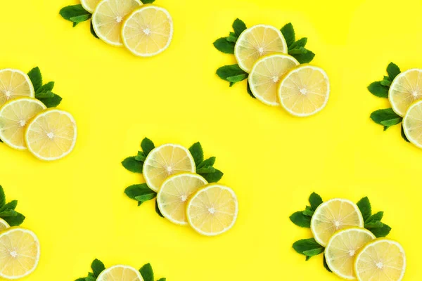 Ripe lemons pattern. Three slices of lemon lie on mint leaves on bright yellow background. Tropical fruits on background. Fresh citrus