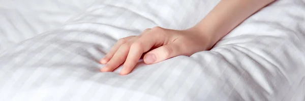 Güneş ışınlarında beyaz çarşafların üzerinde güzel bir kadın eli. Seçici odaklanma. Pankart
