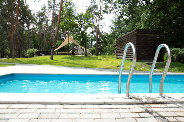 Swimming pool with stair. Clear and blue, clear water in the pool. Grab bars ladder in the blue swimming pool. Side view