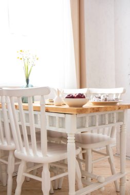 İçi beyaz mobilyalarla dolu yemek odası, ahşap tezgahlı masa ve beyaz sandalyeler. Yeni modern mutfak. Minimalizm. Üst görünüm