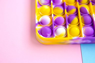 Parlak renkli anti-stres oyuncağı patlat. Boş pembe ve mavi arka planda yeni oyuncaklar. Kapat.