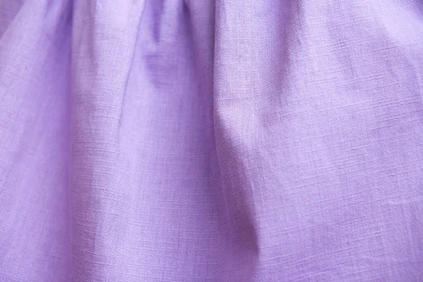 Beautiful nude violet fabric texture with folds and contrasting shadows . Draped background of purple cotton, texture. Copy space. Close up