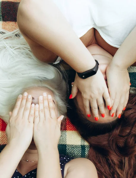 Δύο γυναίκες βάζουν τα χέρια τους πάνω από τα μάτια τους μαζί. Οι γυναίκες ξαπλώνουν ανάσκελα σε μια κουβέρτα στο πάρκο. — Φωτογραφία Αρχείου