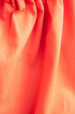 Katları ve zıt gölgeleri olan güzel turuncu kumaş dokusu. Parlak pamuktan, dokudan örtülü bir arka plan. Dikey arkaplan. Kapat.