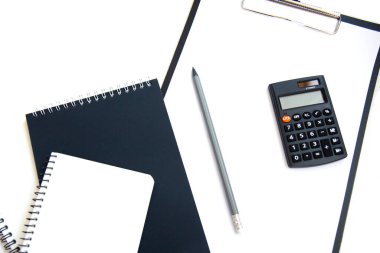 Hesap makinesi, kağıt para ve beyaz arka planda izole edilmiş defter. Borç yönetimi, vergi ödeme ve yatırım kavramı