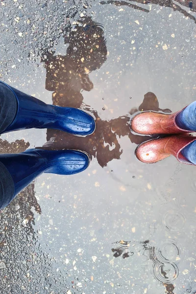 Maman et fille marchent dans des bottes en caoutchouc à travers les flaques d'eau en automne — Photo