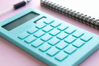 Pembe zemin üzerinde nane hesap makinesi, defter ve kalem