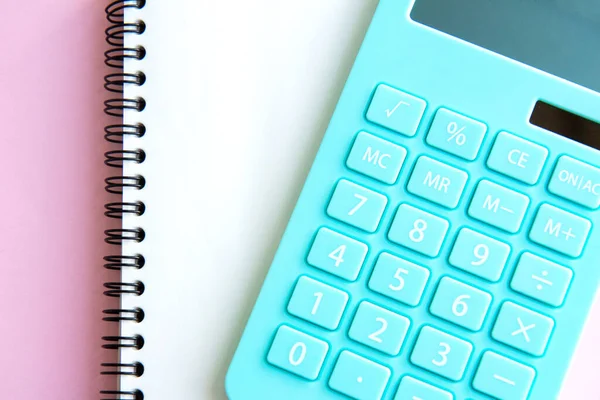 Pembe arka planda izole edilmiş naneli hesap makinesi ve defter. Aile bütçesi kavramı ve vergi ödemeleri, yatırımlar. Üst görünüm