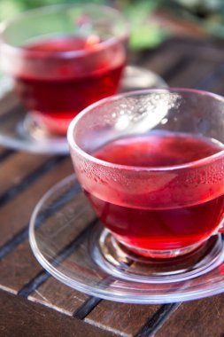 Terastaki ahşap tepside sıcak kırmızı amberçiçeği çayı. Kapat.