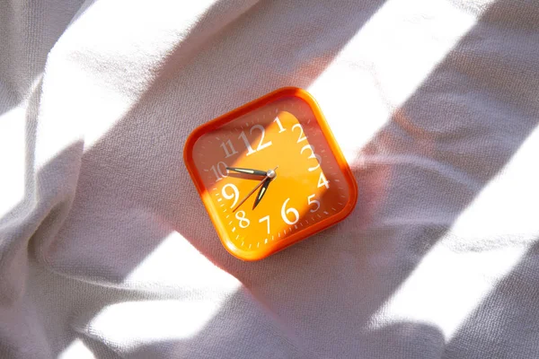 Orange Alarm Clock Ray Sun White Blanket Contrasting Shadows — Stock Photo, Image