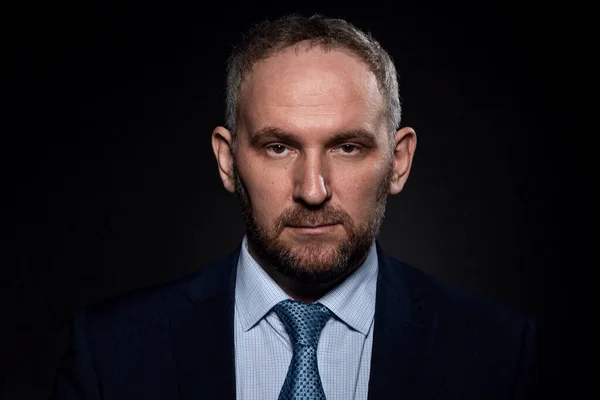 Siyah arka planda takım elbiseli bir adam.