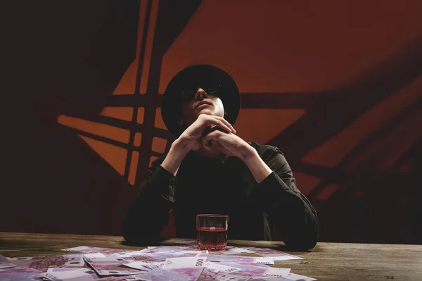 Para dolu bir masada, siyah gözlüklü havalı bir adam.