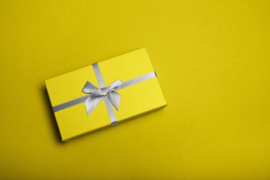 Arka planda sarı ve gri aydınlatıcı Noel hediyesi kutusu yatıyordu.