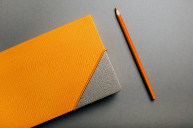 Sarı günlük ve kalem gri arka planda, düz yatıyordu.