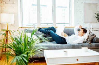 Kanepede otururken dizüstü bilgisayar kullanan bir kadın.