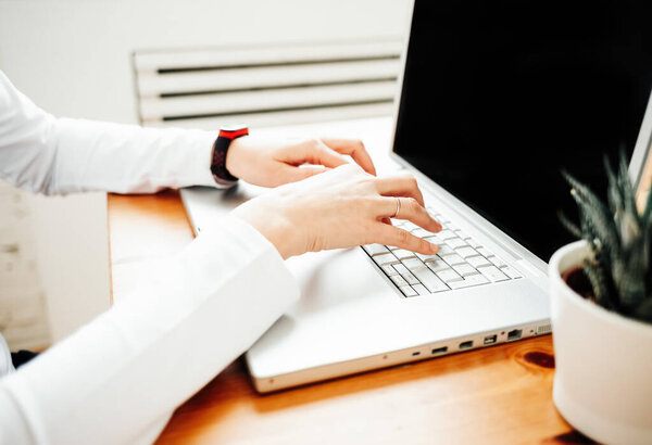 Women's hands work on the notebook, remotely at home