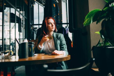 Bir kafede yeşil çay içen genç kız pencereden dışarı bakıyor.