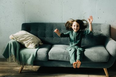 Çocuk evdeki kanepeye atlıyor, karantina sırasında evde eğleniyor.