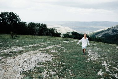Bir çocuk dağlarda yürür