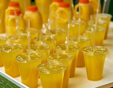 Plastik bardaklarda taze sıkılmış meyve suyu dolu bir tepsi.