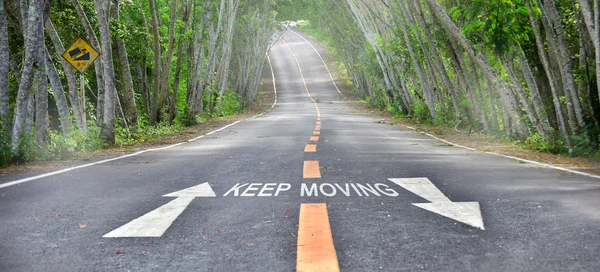 Palabras de seguir moviéndose con flecha blanca y marca de línea amarilla en la carretera — Foto de Stock