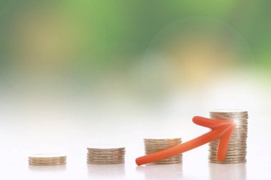 Soyut arkaplanda yukarı doğru kırmızı oku olan bozuk paralar yığını. İleride sürdürülebilir kalkınma kavramı ve ekonomik büyüme ticaret fikri