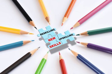 New skills development concept and changing skill demand idea. Reskilling, upskilling and new skills written on blue puzzle with colored pencils isolated on white background clipart