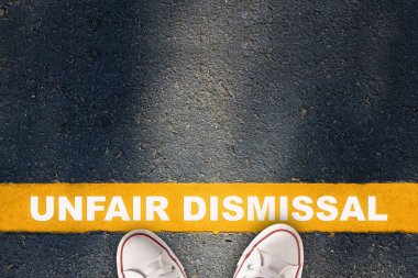 Unfair dismissal written on yellow line on asphalt road background. Employee termination concept and economic recession idea clipart