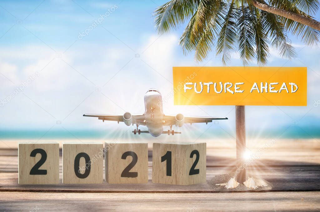 New year 2021 to 2022 and commercial plane with future ahead word on wooden sign on tropical beach background. Happiness holiday travel concept and business transportation recovery after covid-19 idea