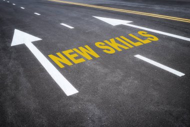 New skills word and yellow arrow on asphalt road with marking lines for separate lane. Reskilling and upskilling development concept and changing skill demand idea clipart