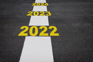 Yeni yıl 2022 'den 2024' e kadar asfalt yol yüzeyinde işaretleme çizgileri var. Ticari üretken başarı kavramı ve düzelme fikri