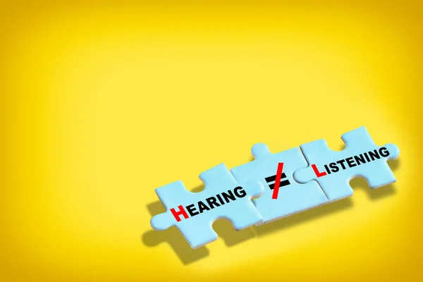 stock image Hearing is not same as listening written on blue puzzle isolated on yellow background. Business leadership concept and teamwork to communication idea